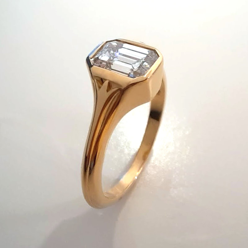 Flowers engagement ring signetring in 18K yellow gold with a stunning 0.93 ct. diamond in emerald cut and two abstract flowers on the sides Daphne Meesters Jewellery Designer Goldsmith The Hague Netherlands