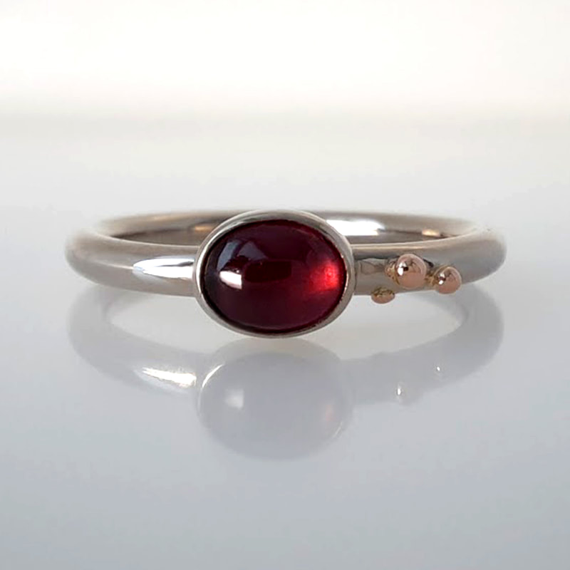 Stellina ring 14K white gold round wire ring with red gold balls and a oval spinel in a burgundy colour designer goldsmith Daphne Meesters Jewellery The Hague Netherlands